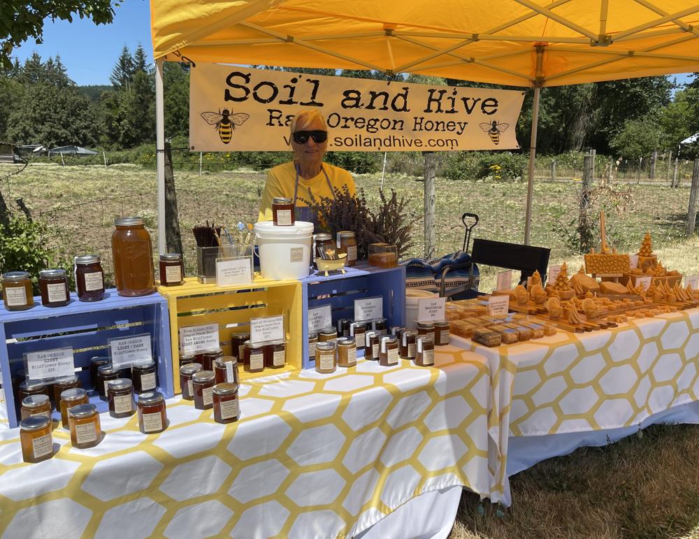 The Soil and Hive tasting table set with jars of raw honey, honeycomb, and hand-poured beeswax candles